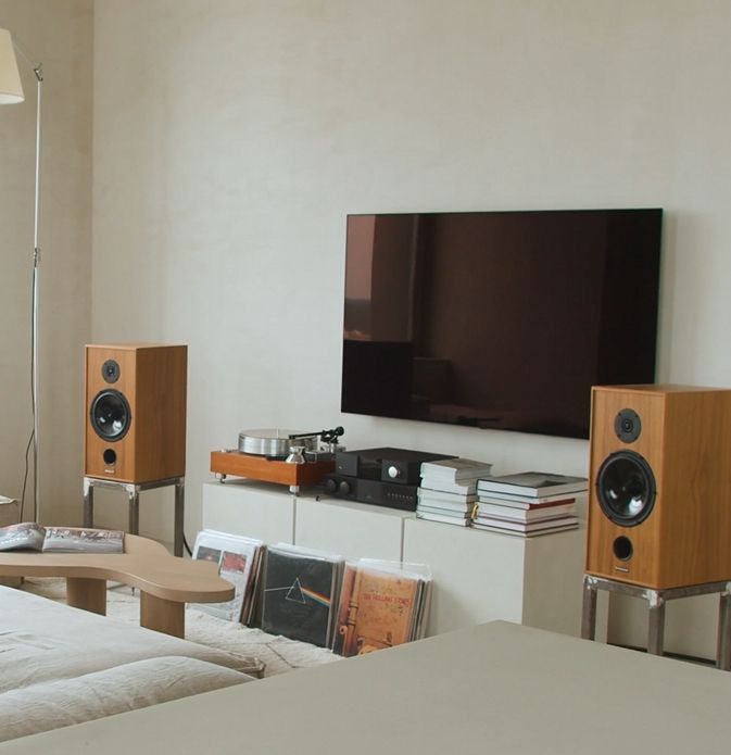 Living room with speakers, TV, stereo equipment, and records on a white cabinet.