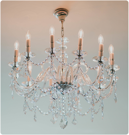 Crystal chandelier with lit candle-style bulbs, hanging from a white ceiling.