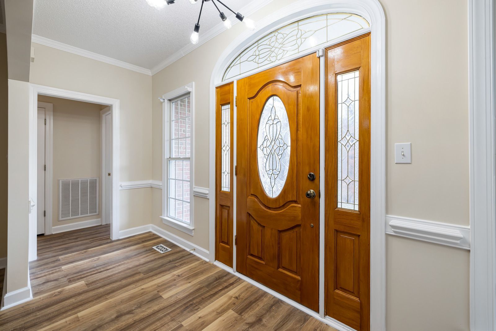 Wooden front door with sidelights, arched transom, and interior hallway.