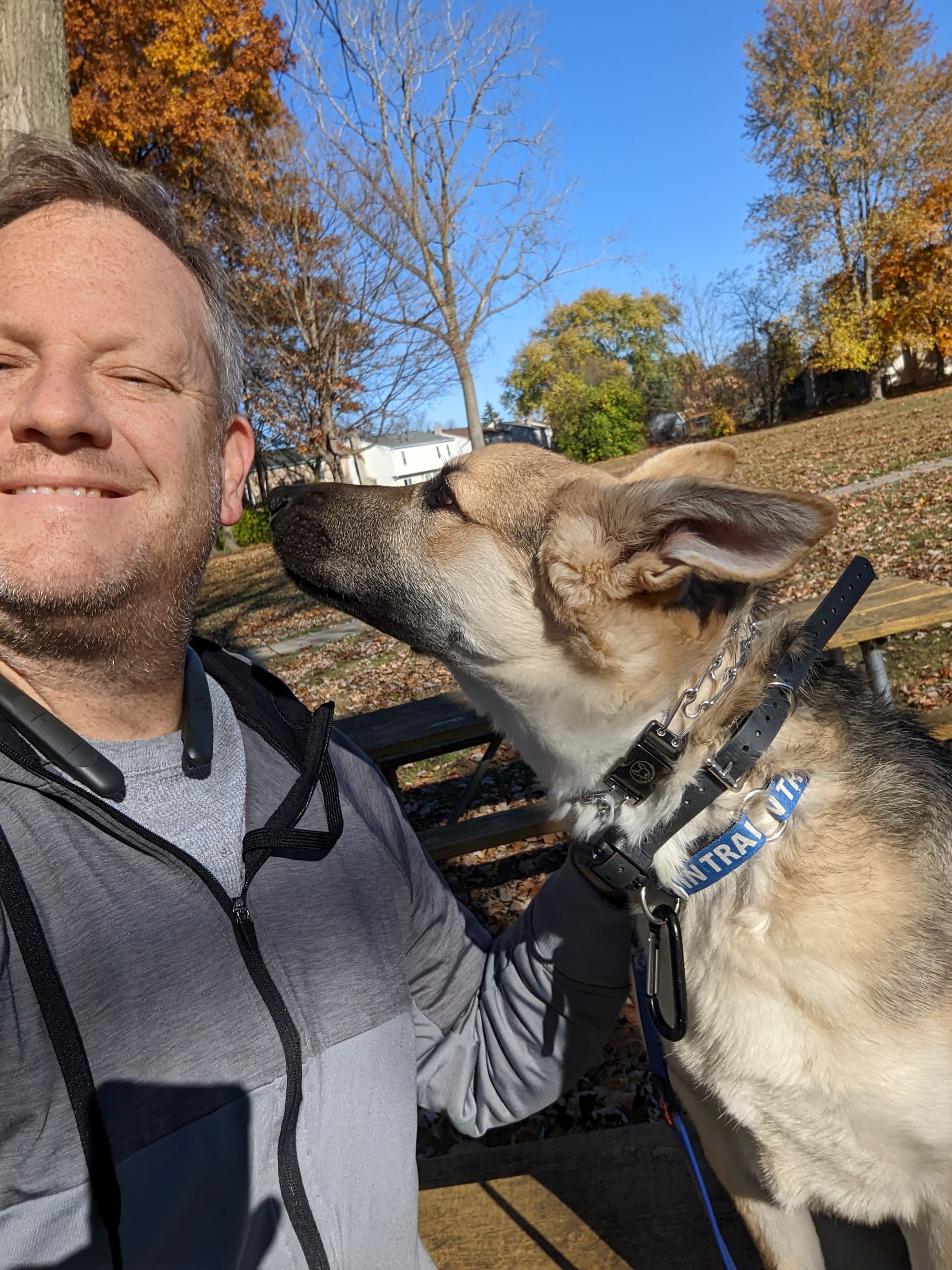 A man is standing next to a dog that has a collar