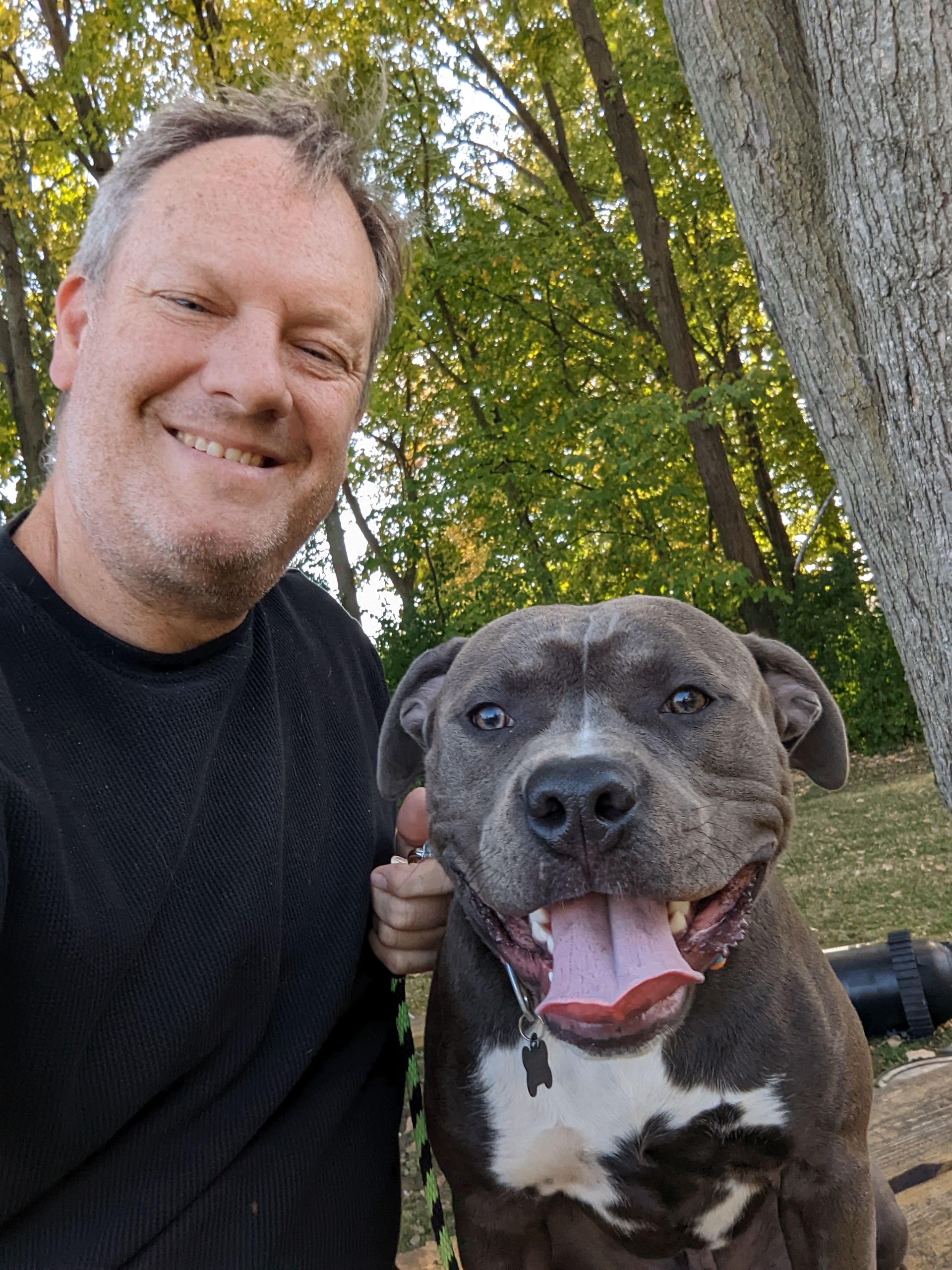 A man is posing for a picture with his dog