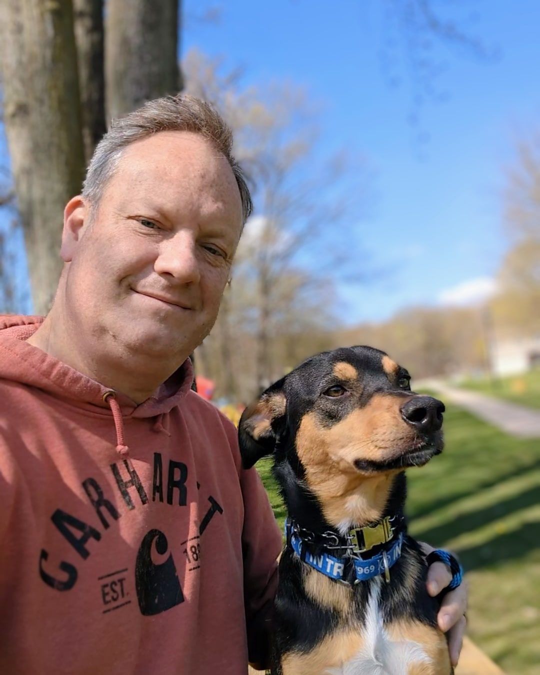 A man wearing a sweat shirt is holding a dog