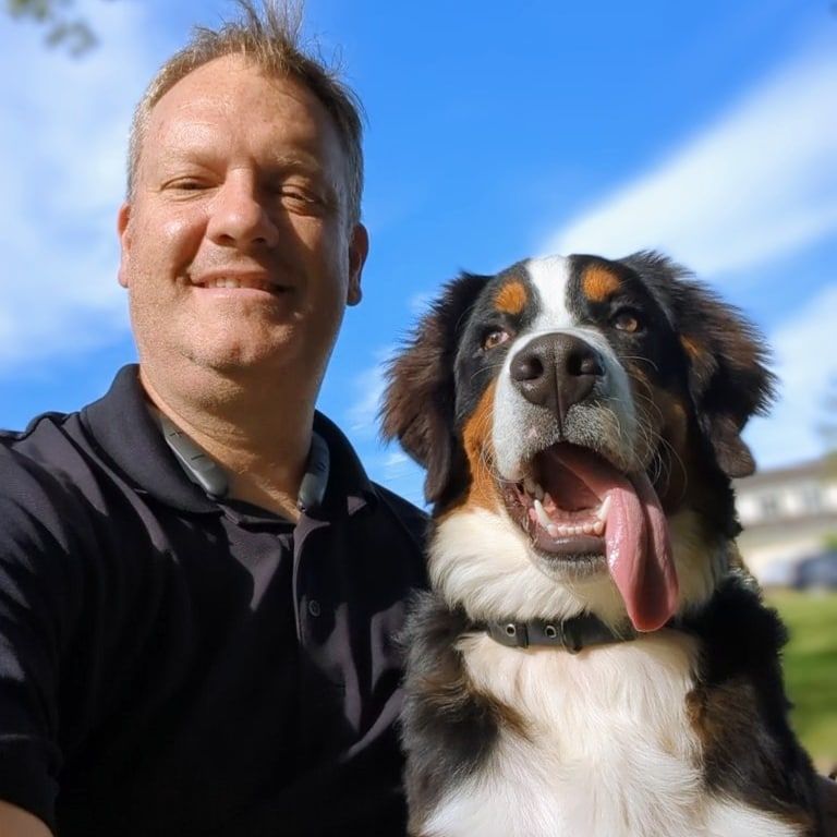 A man is standing next to a large brown and white dog.