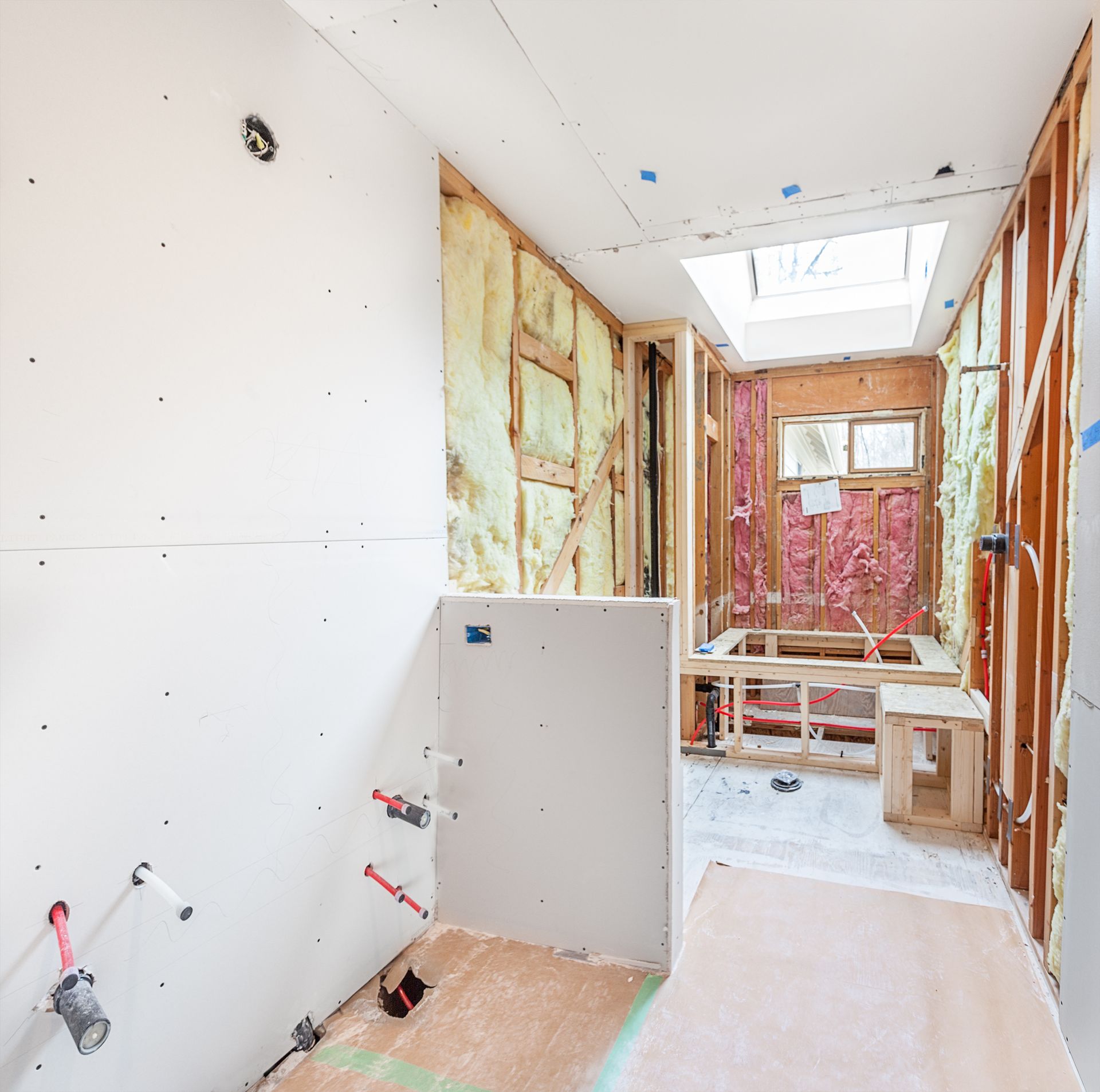 Bathroom under construction, drywall and studs visible, insulation, plumbing fixtures, skylight. Bathroom under construction, drywall and studs visible, insulation, plumbing fixtures, skylight.