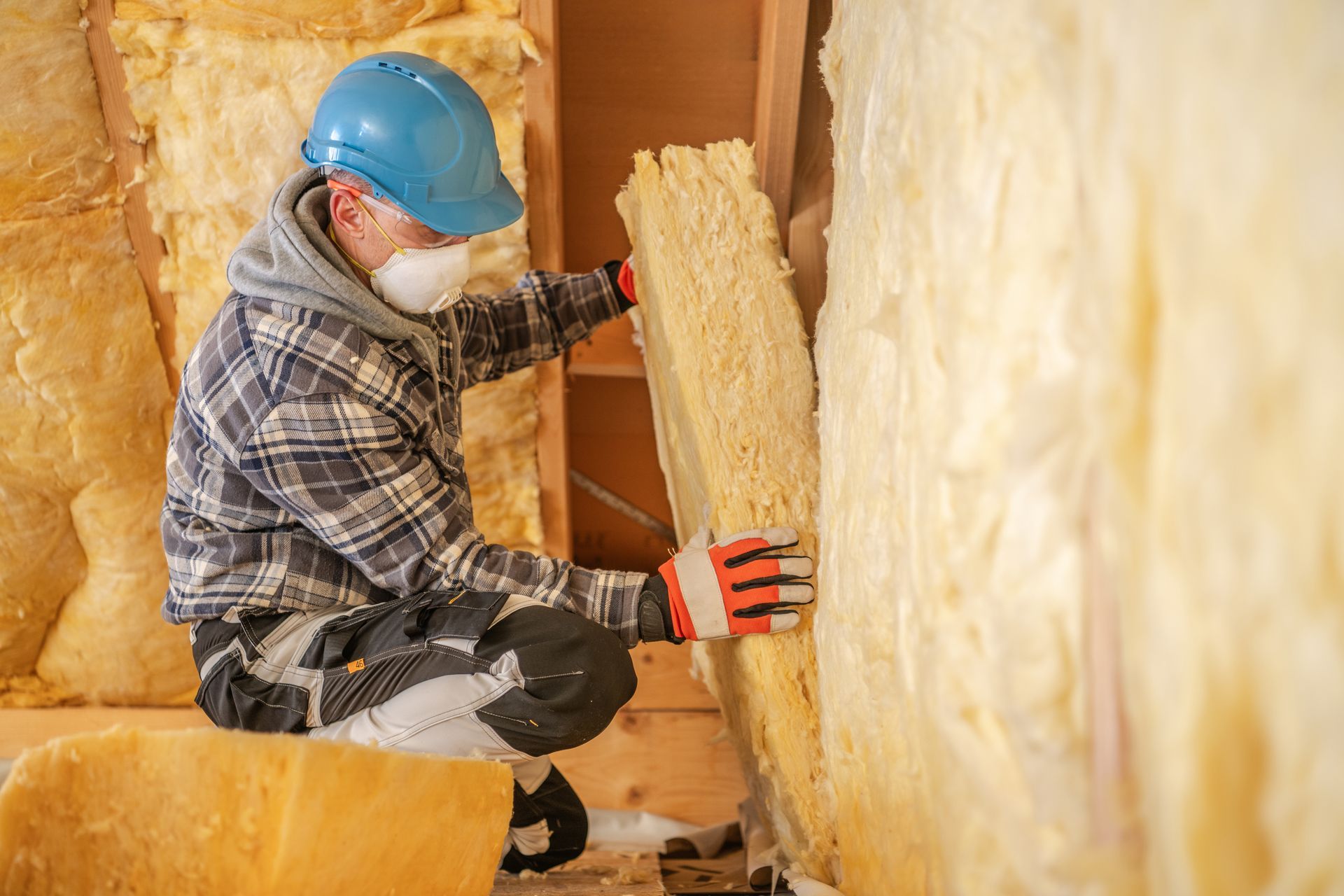 Man in black suit using hose to insulate plywood-lined room. Interior setting, door visible. Man in black suit using hose to insulate plywood-lined room. Interior setting, door visible.