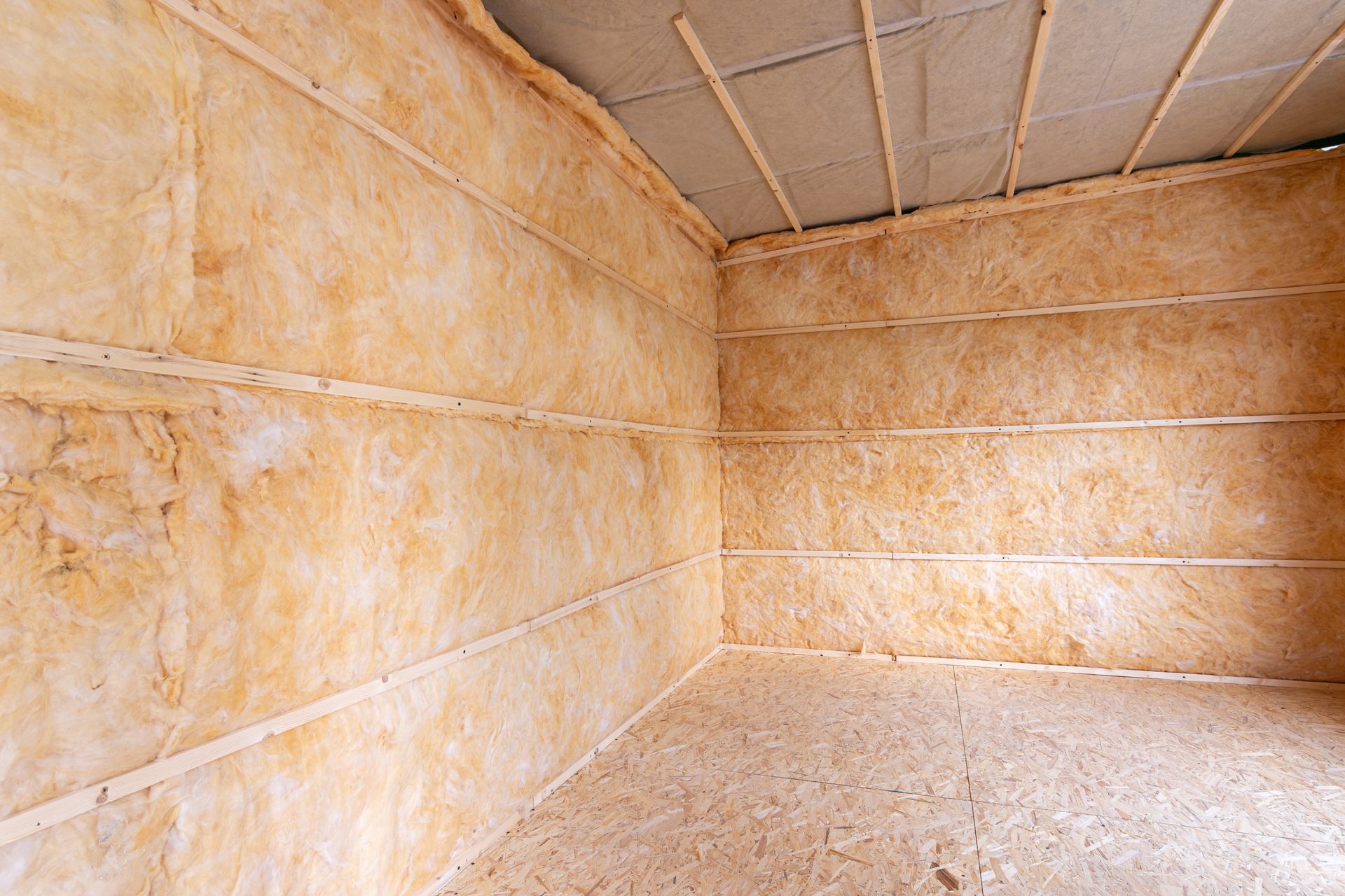 Interior of a room with insulation installed on the walls, and ceiling. Brown and tan colors.