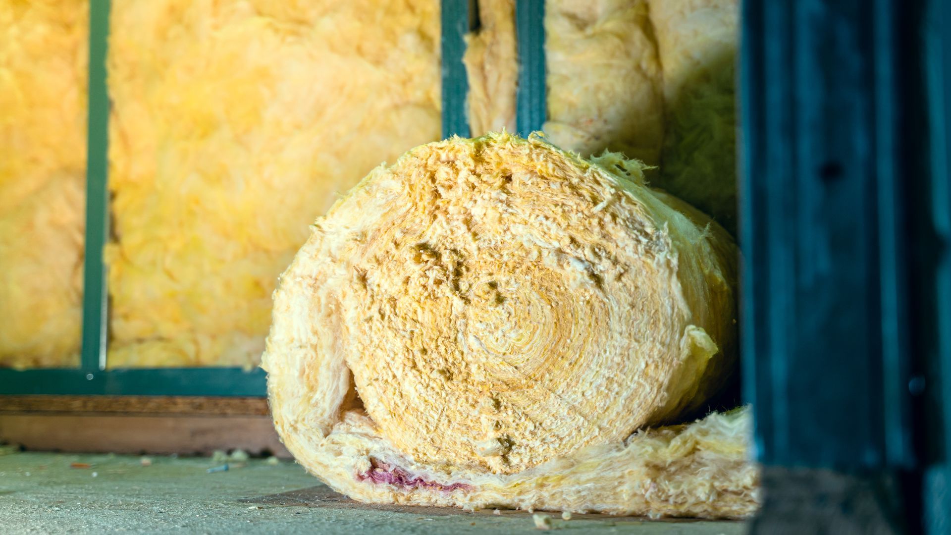 Rolled insulation material inside a wooden frame, yellow color.