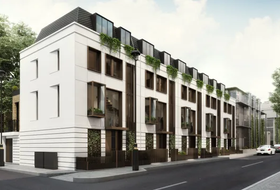 Modern white townhouses with dark window frames and black awnings along a city street.