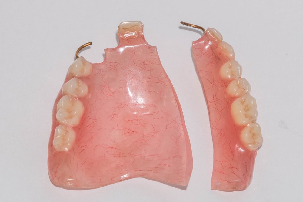 A Broken Denture Is Sitting On A White Surface — Alice Denture Clinic In Ciccone, NT