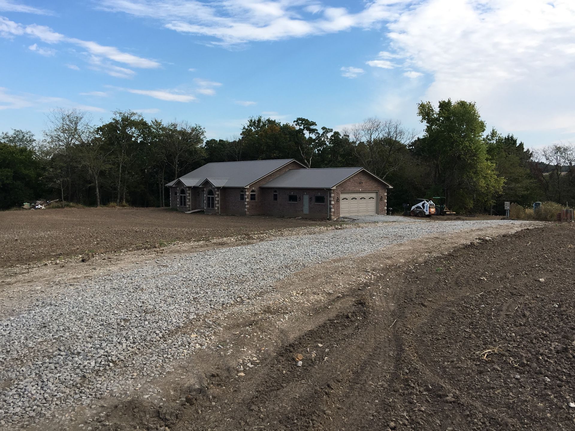 A house is sitting in the middle of a gravel road