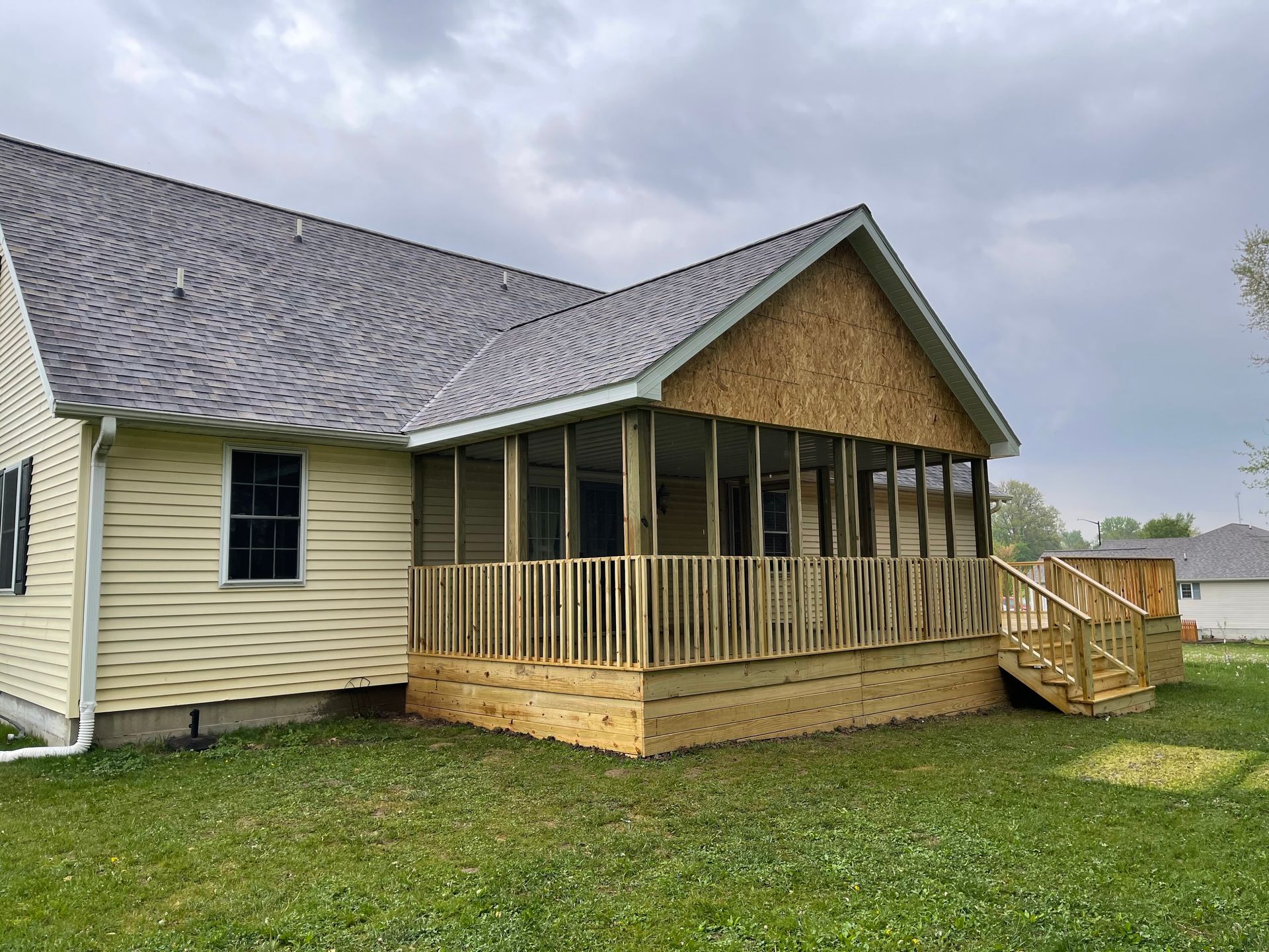 A house with a screened in porch and a wooden deck.