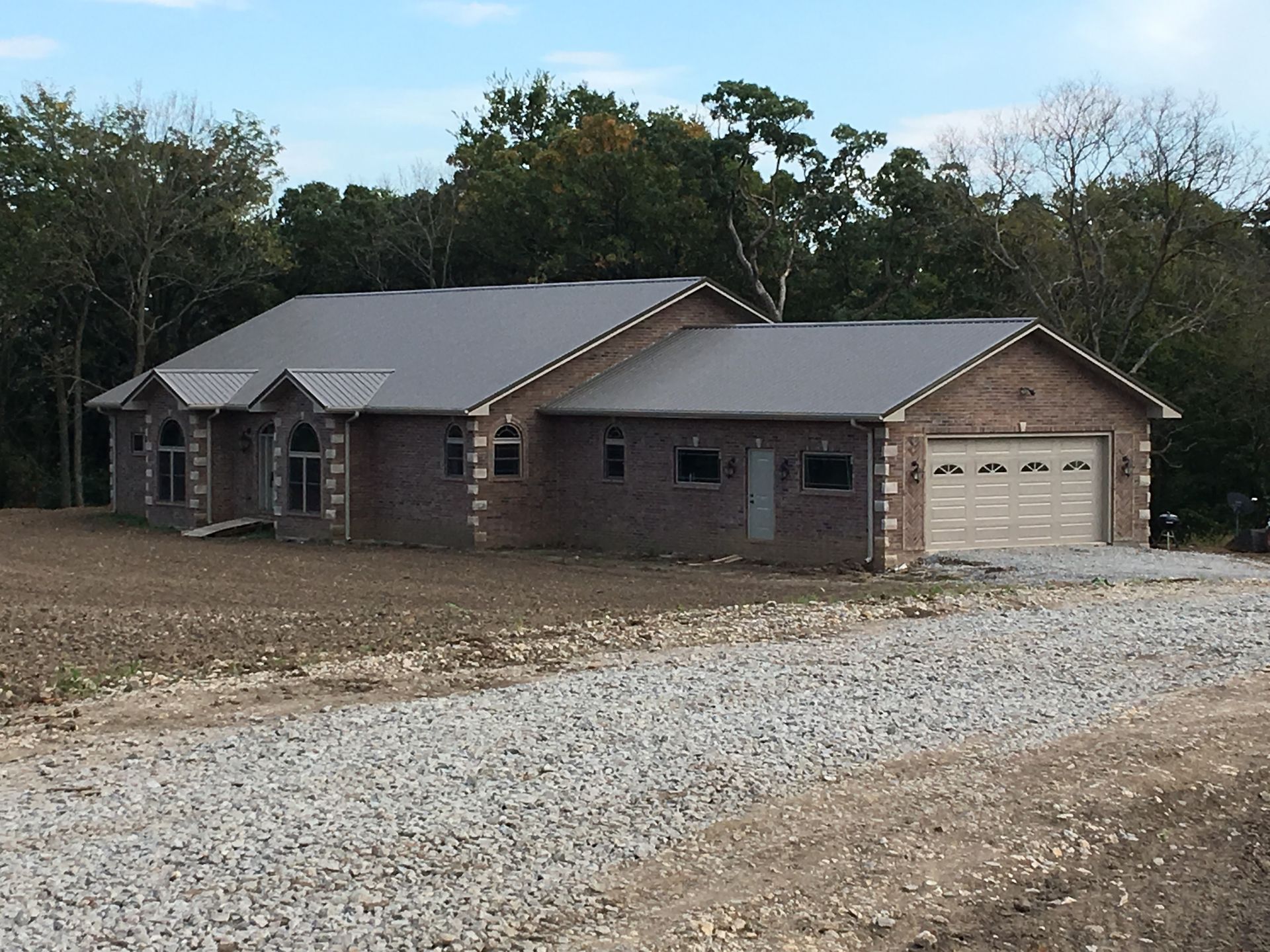 A brick house with a metal roof and a garage