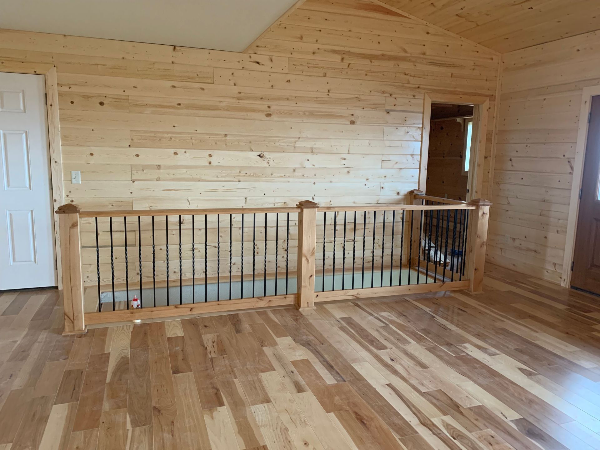 A living room with hardwood floors and a wooden railing.