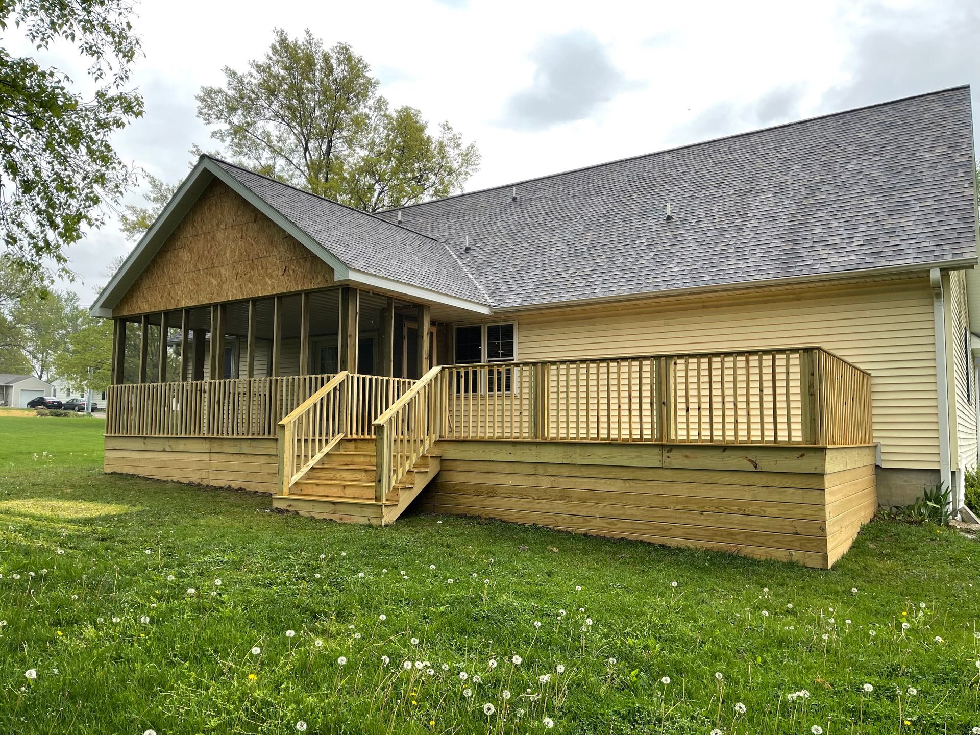 A house with a screened in porch and a wooden deck.