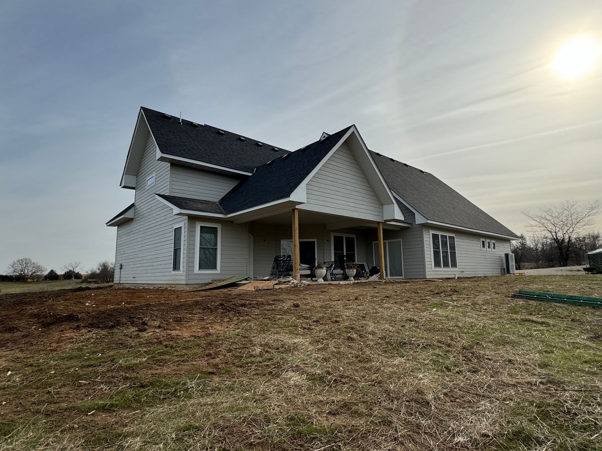 A large white house is sitting in the middle of a grassy field.
