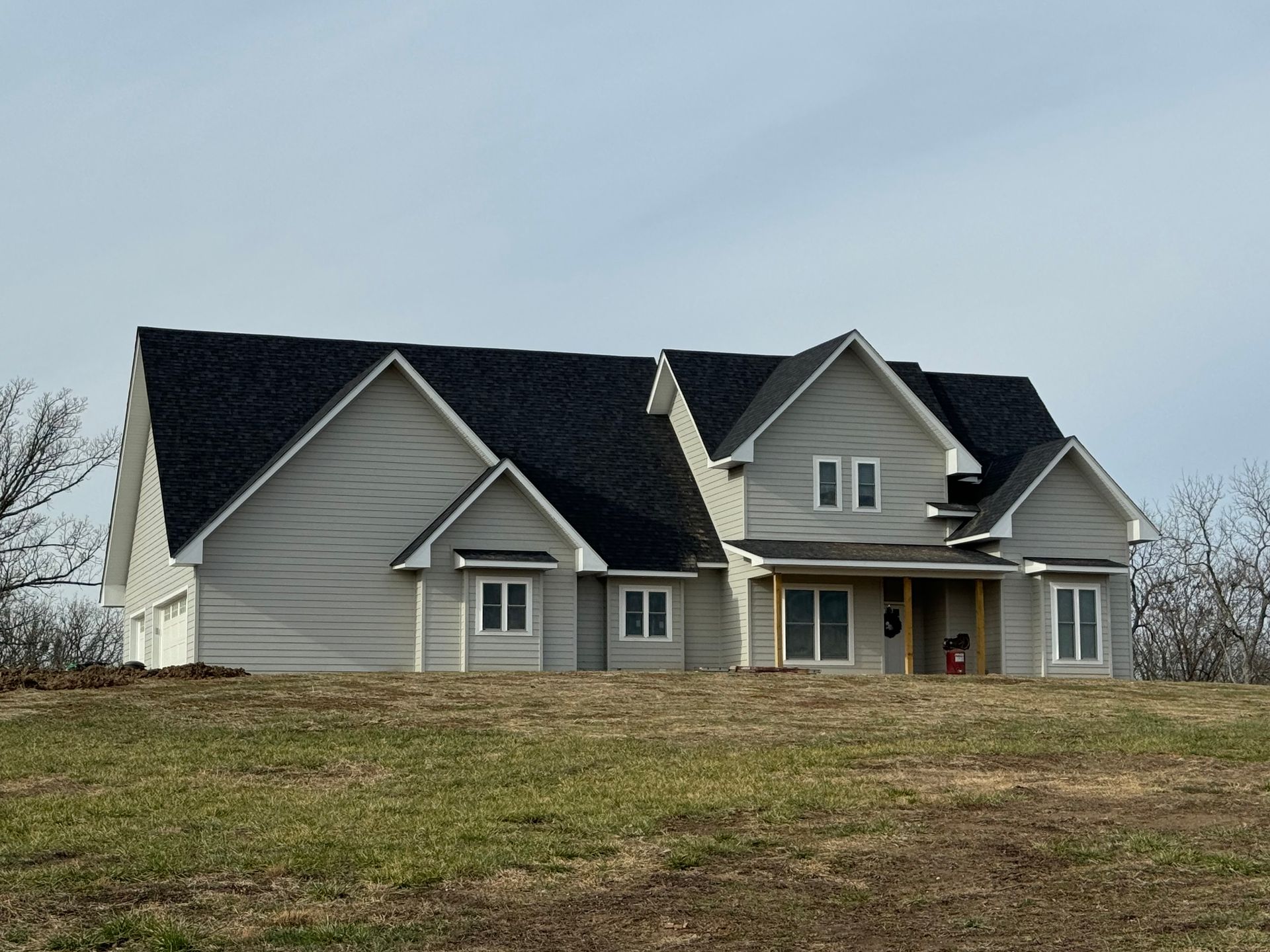 A large house sits on top of a grassy hill