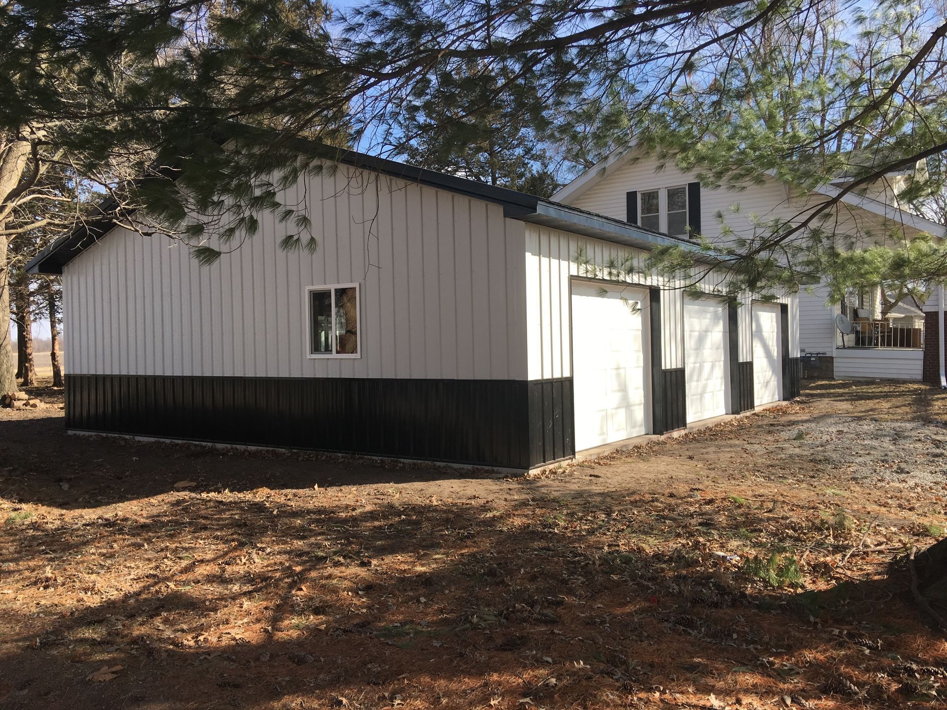 A white and black garage next to a house.