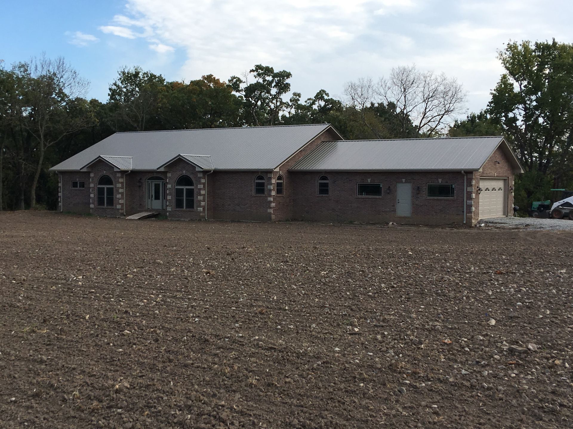 A house is sitting in the middle of a dirt field