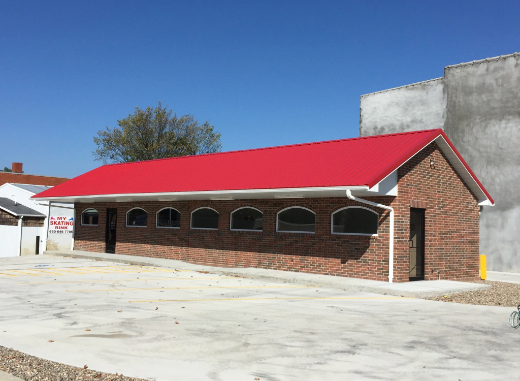 A brick building with a red roof and arched windows