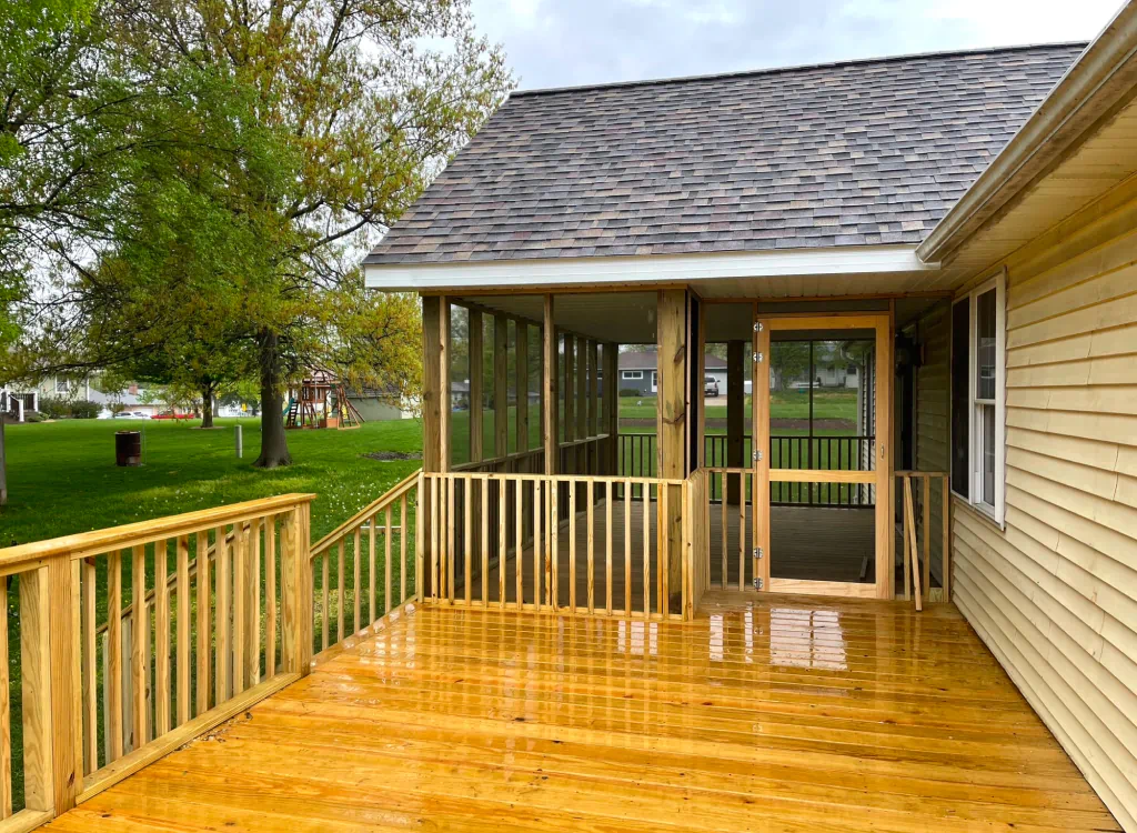 A house with a screened in porch and a wooden deck.