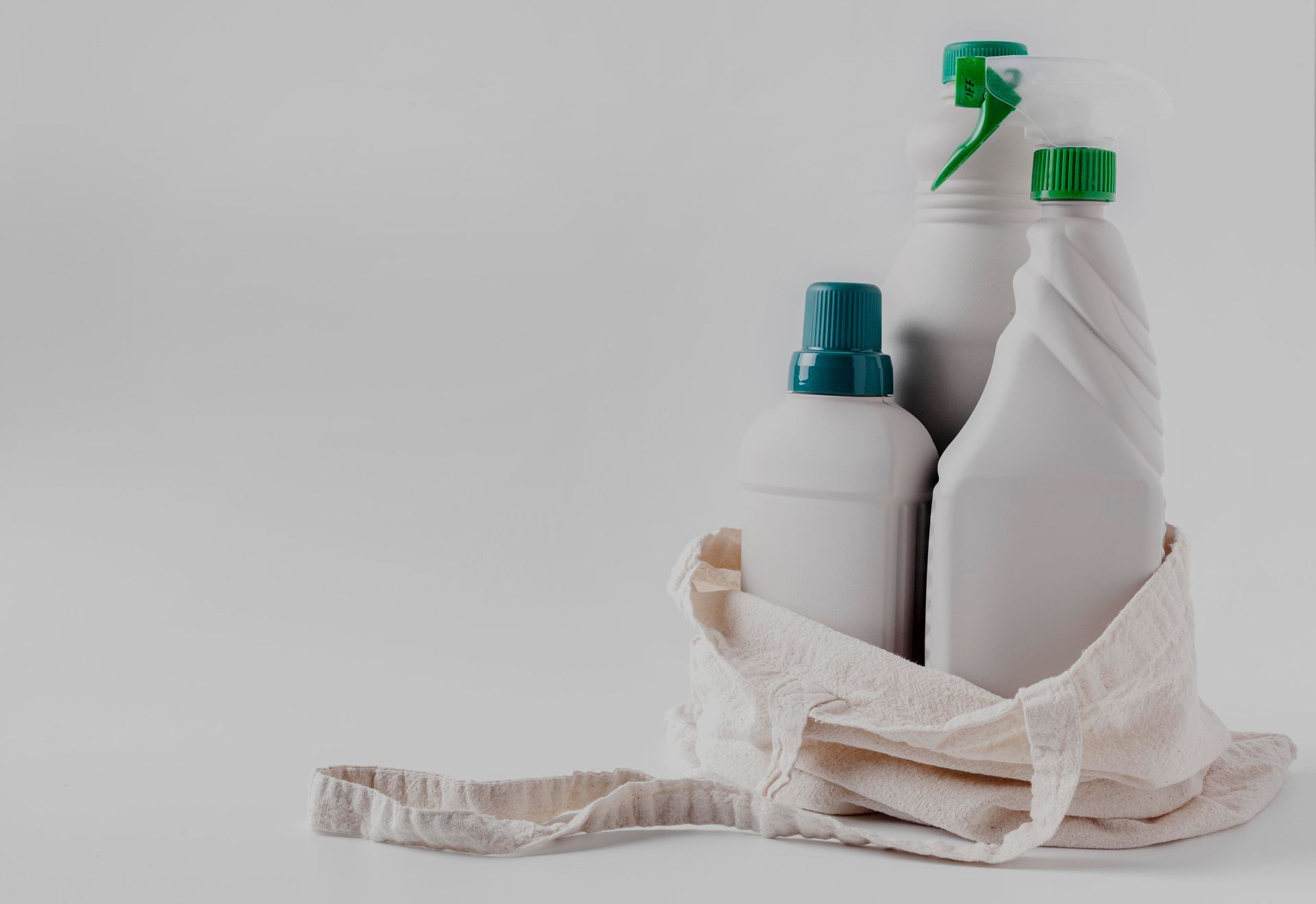 A bag filled with cleaning supplies and a towel on a white background.