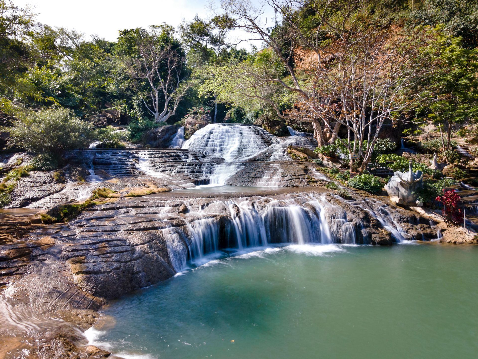 A waterfall is surrounded by trees and rocks in the middle of a forest.