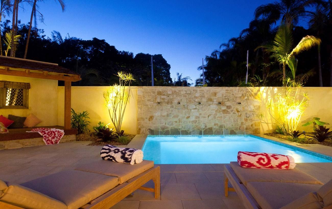 A Large Swimming Pool is Lit Up at Night — Sigley Electrical in Mooball, NSW