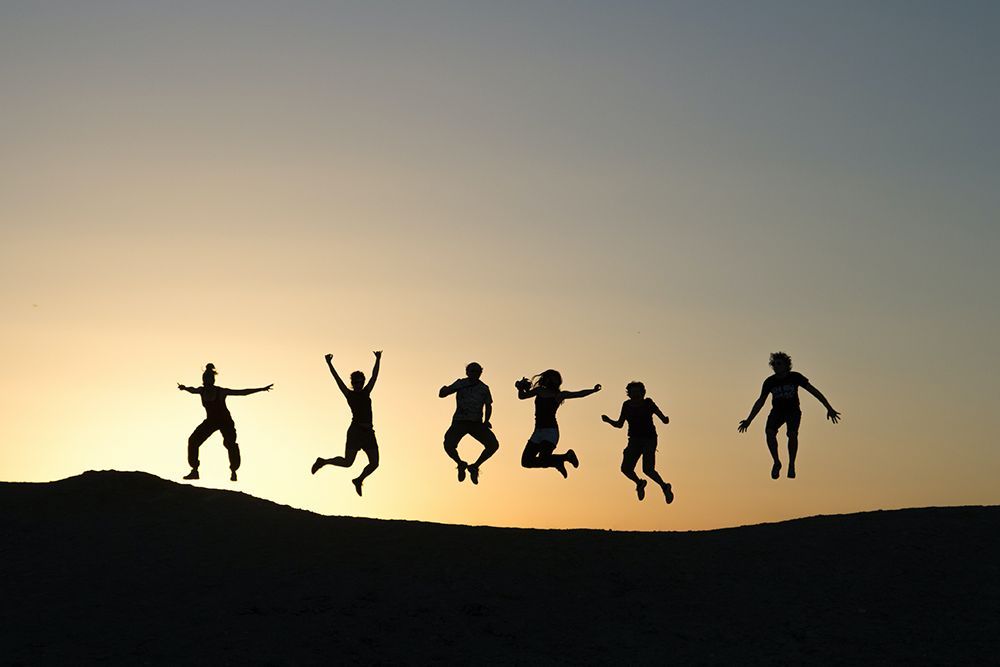 People jumping together during the sunset — Holistic Counselling Sunshine Coast, QLD