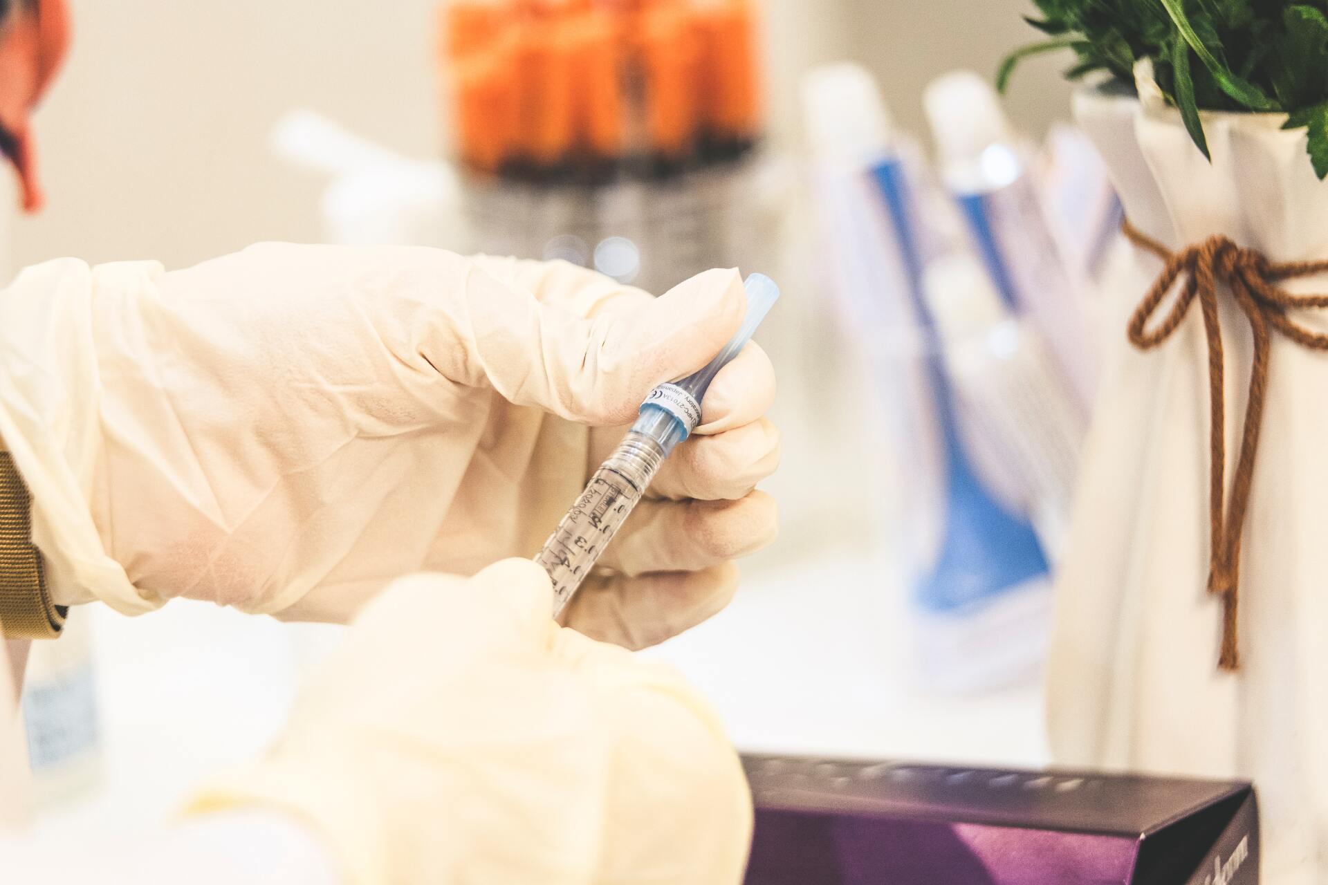 A person wearing gloves is holding a syringe in their hand.