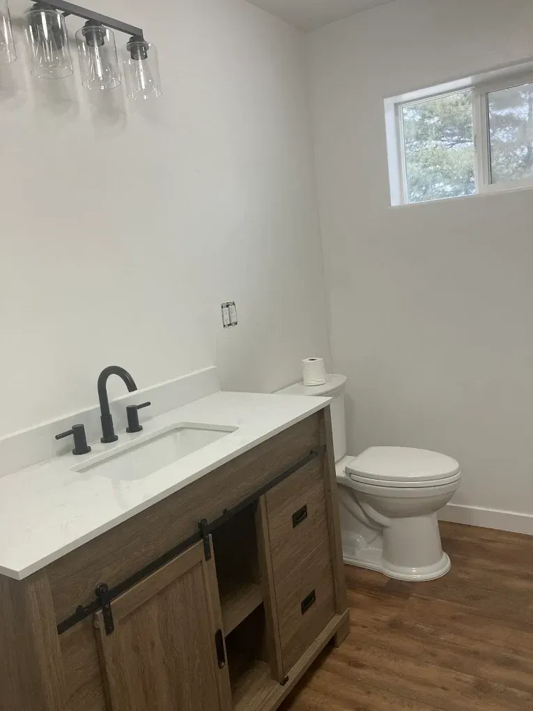 Man on a ladder using a power drill to work on garage door mechanism.