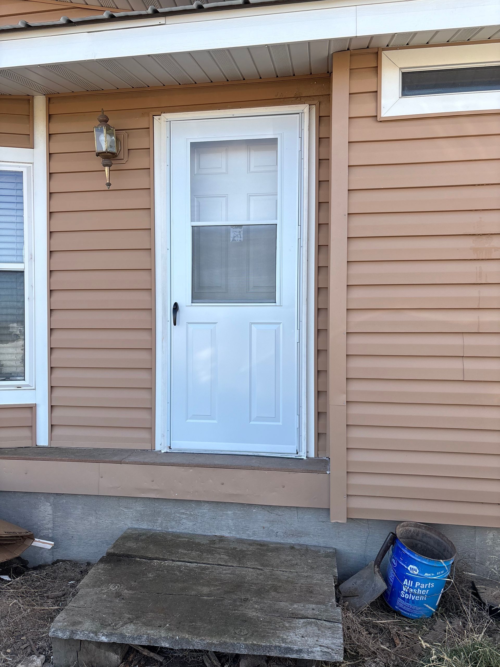 Person in blue gloves using a hammer and pry bar to remove a wooden railing on an outdoor deck.