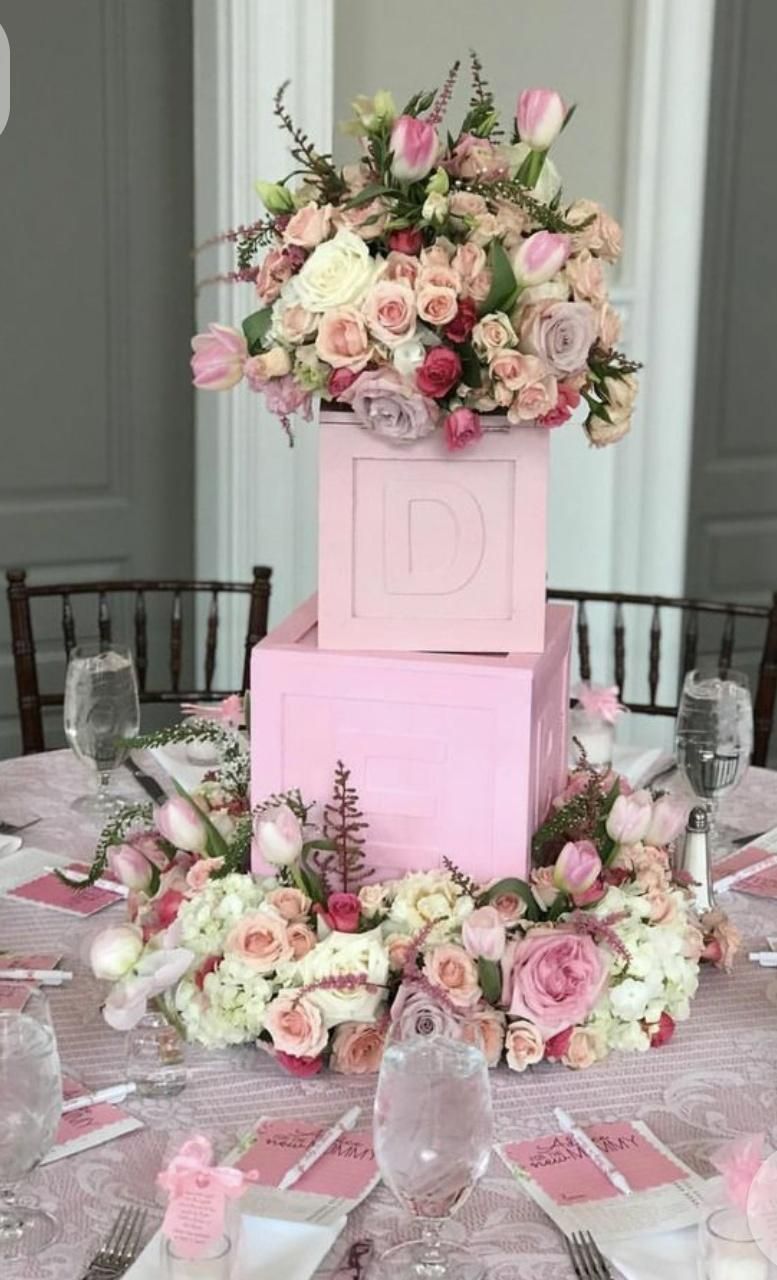 Pink floral table centerpiece with flower arrangements and tiered boxes.