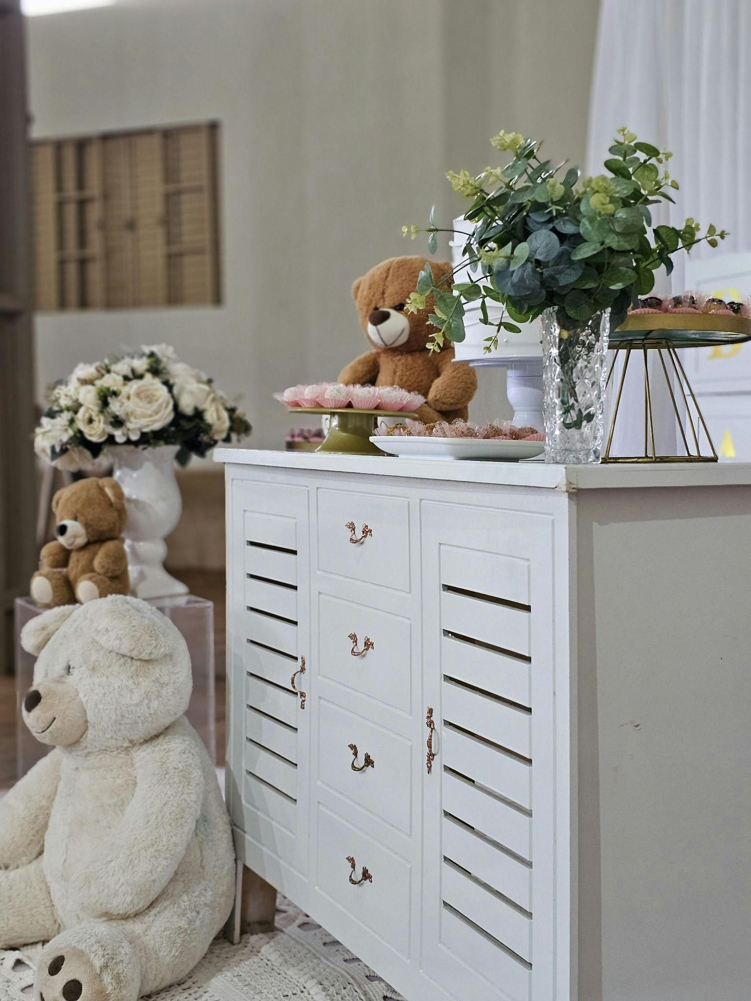 White cabinet decorated for an event with teddy bears, flowers, and treats.