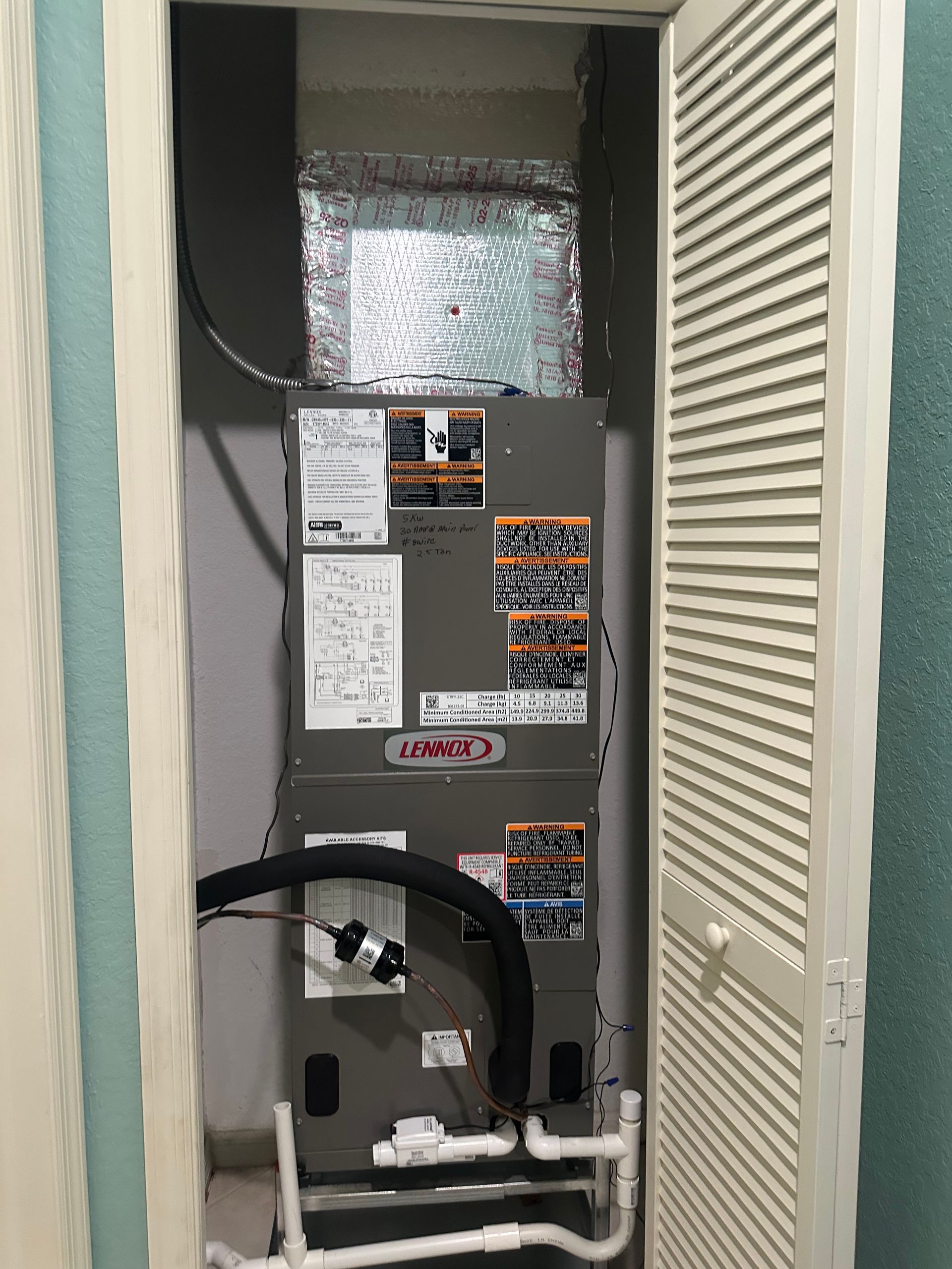 A Lennox HVAC system in a closet, with air ducts, pipes, and a partially open louvered door.