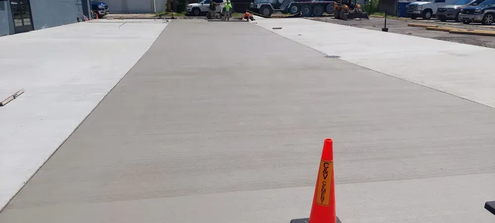 Newly poured concrete with an orange traffic cone. Construction site.