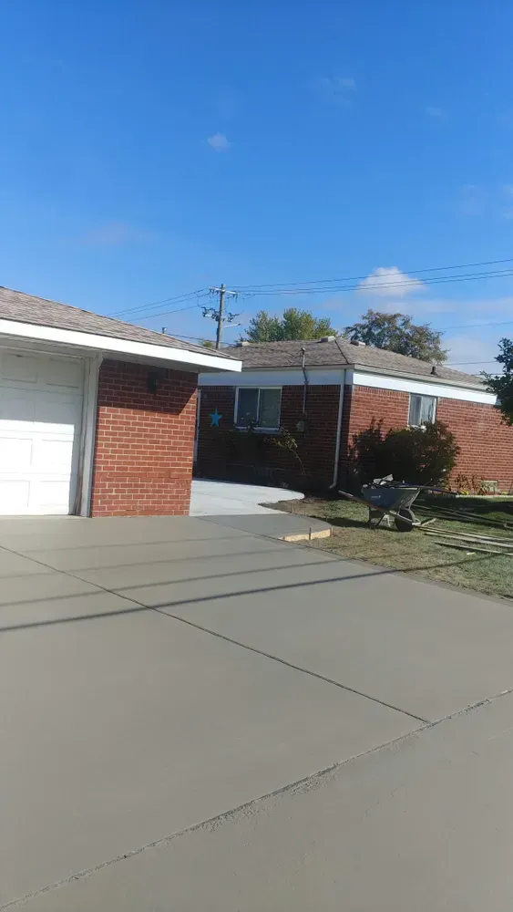 Brick house with attached garage; concrete driveway under blue sky.