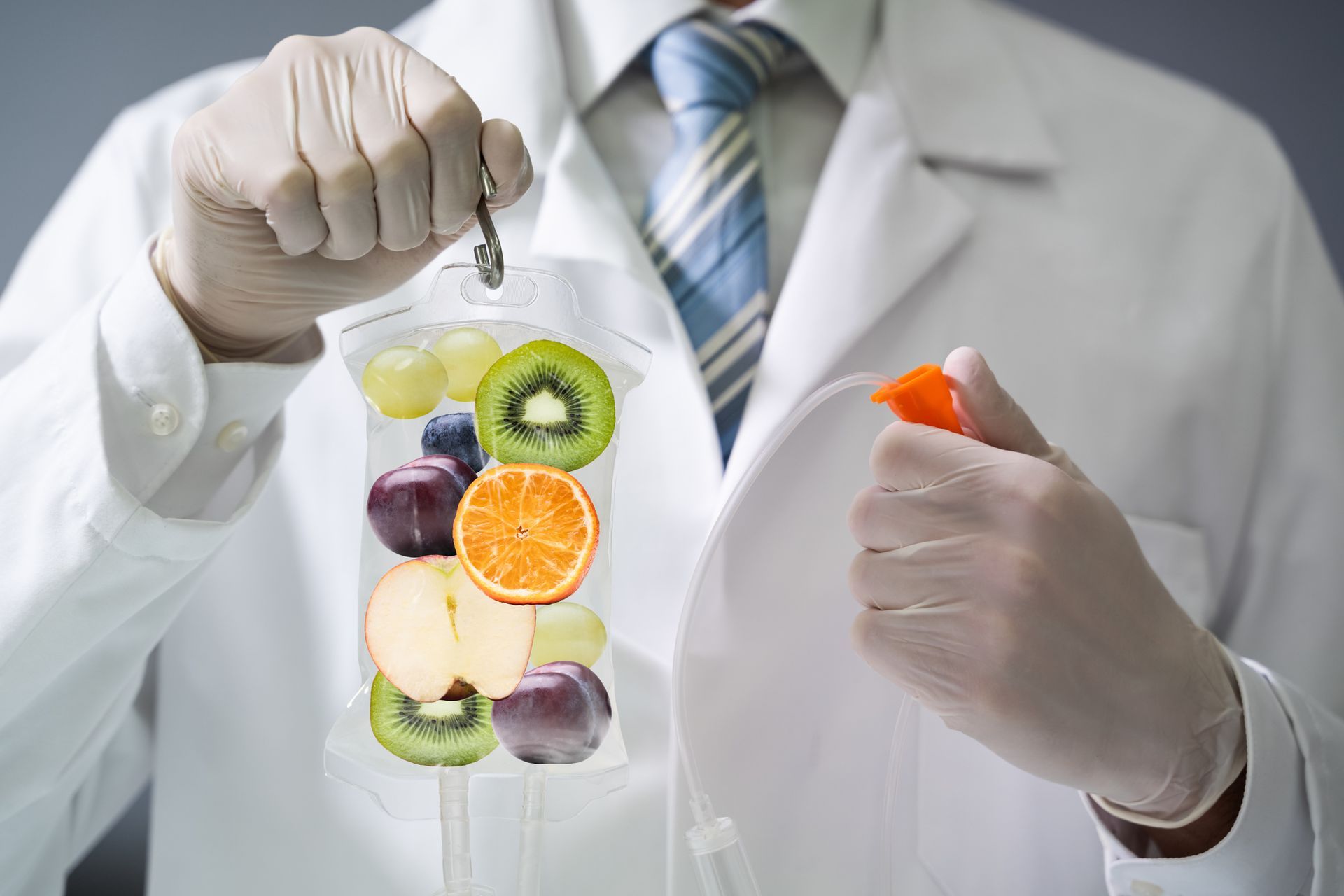 A doctor is holding a bag of fruit in his hand.