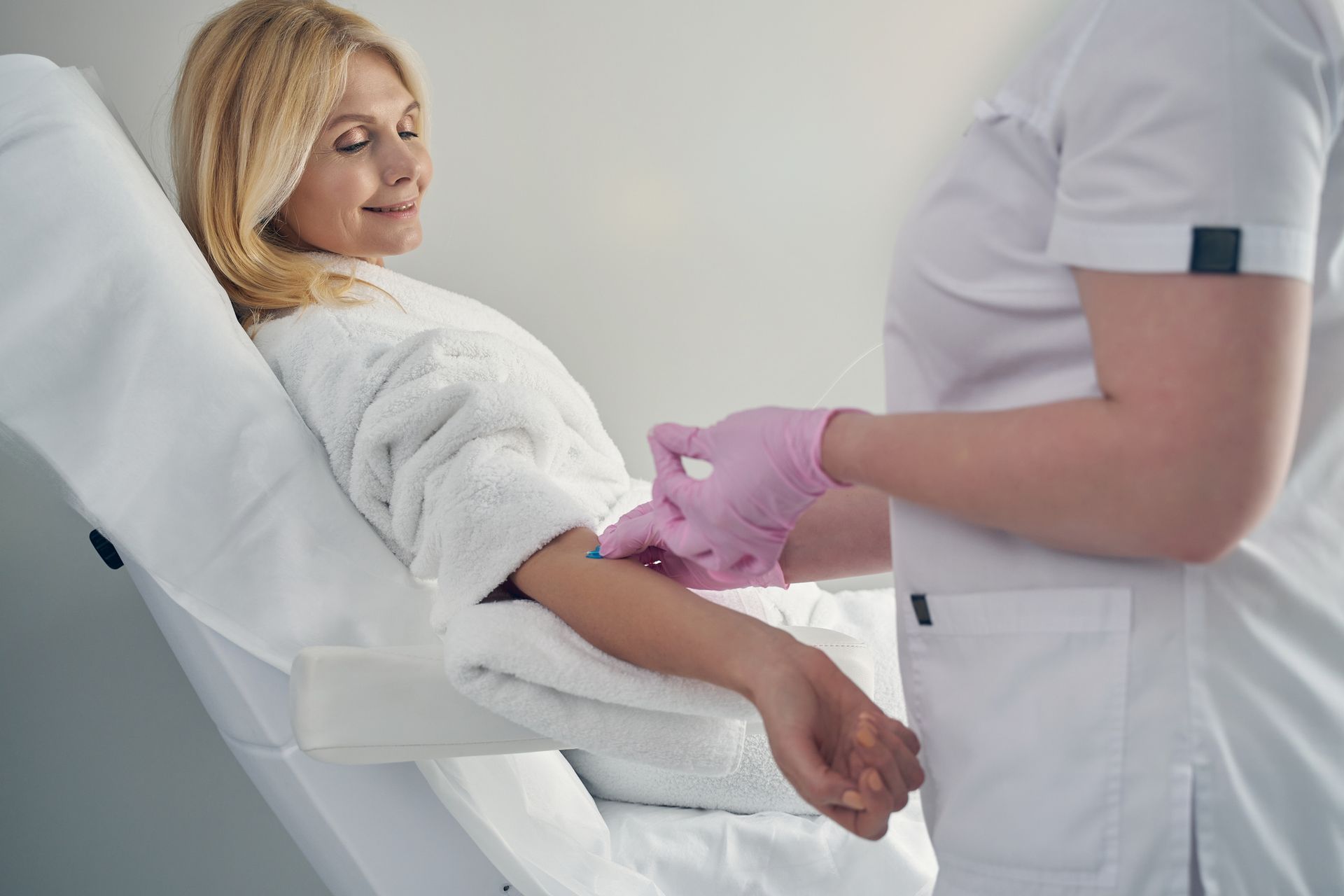 A woman is getting an injection in her arm in a hospital bed.