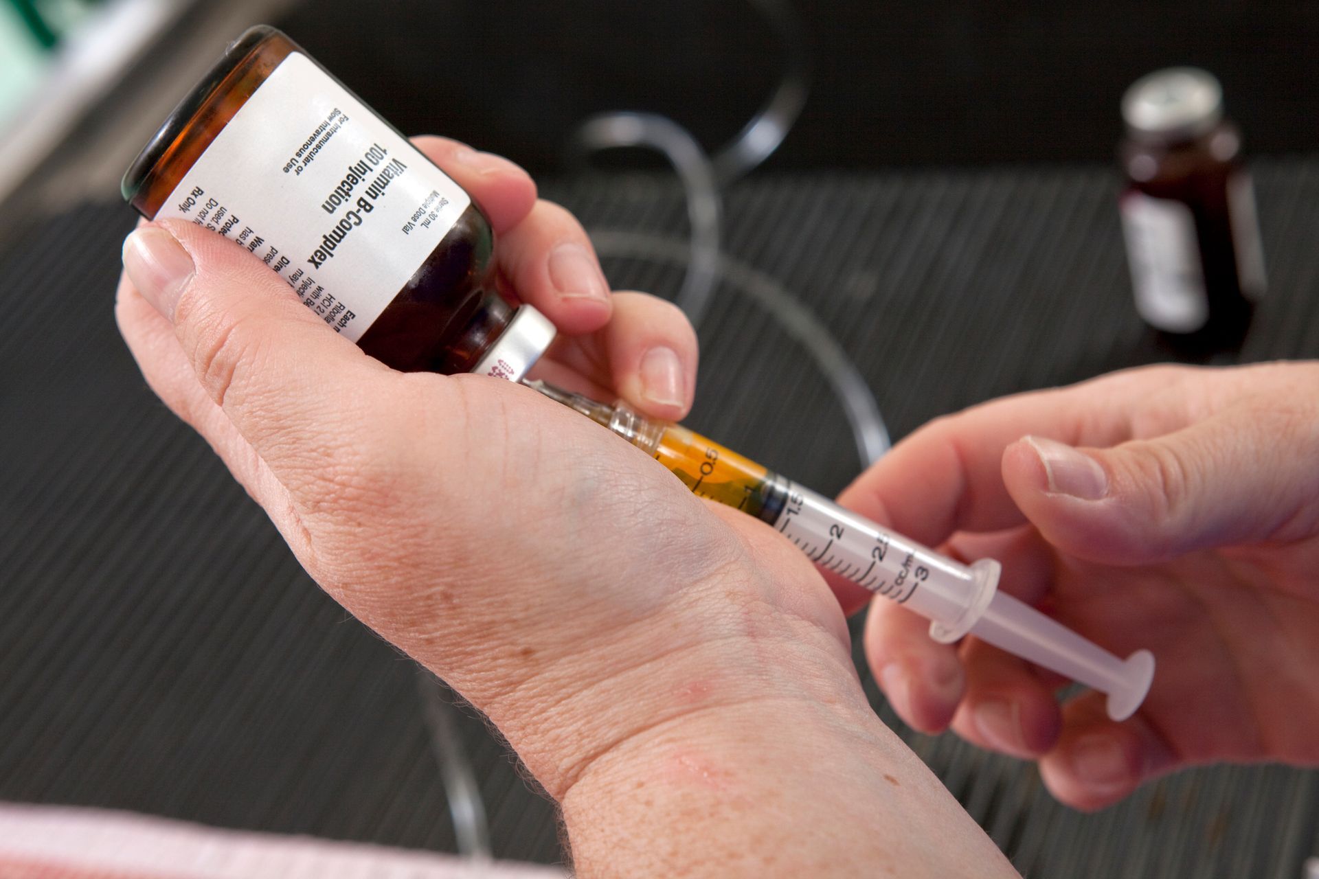 A person is holding a bottle of medicine and a syringe