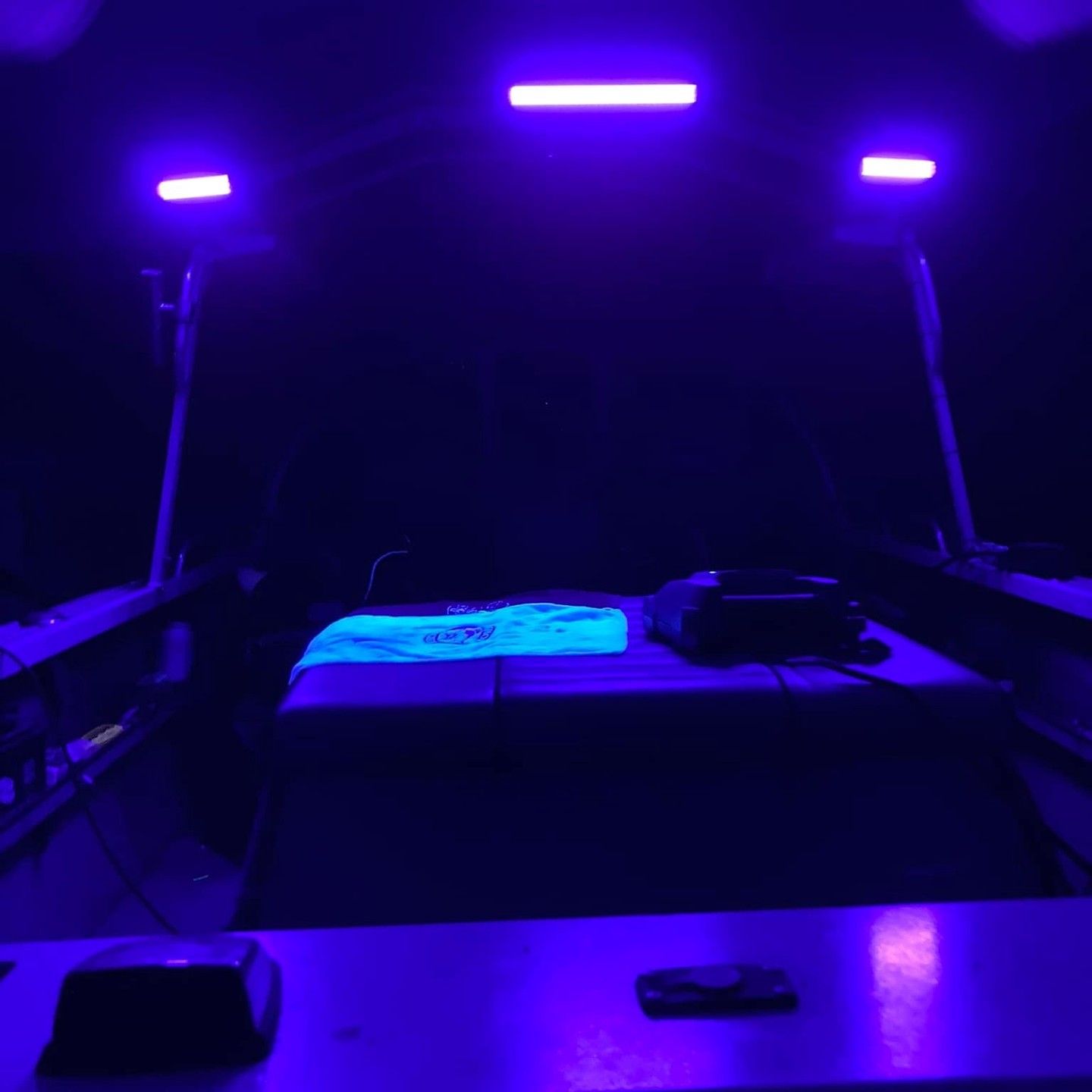 A room with purple lights on the ceiling and a table.