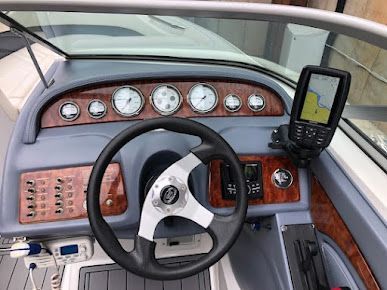 The dashboard of a boat with a steering wheel and a gps.