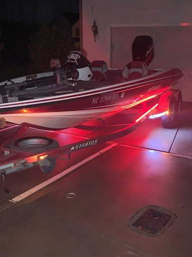 A boat is parked in a garage with red lights on it.