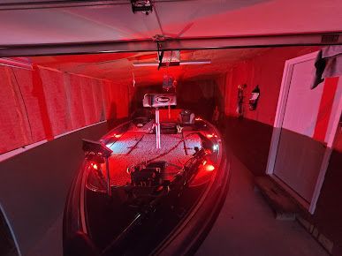 A boat is sitting in a garage with red lights on it.