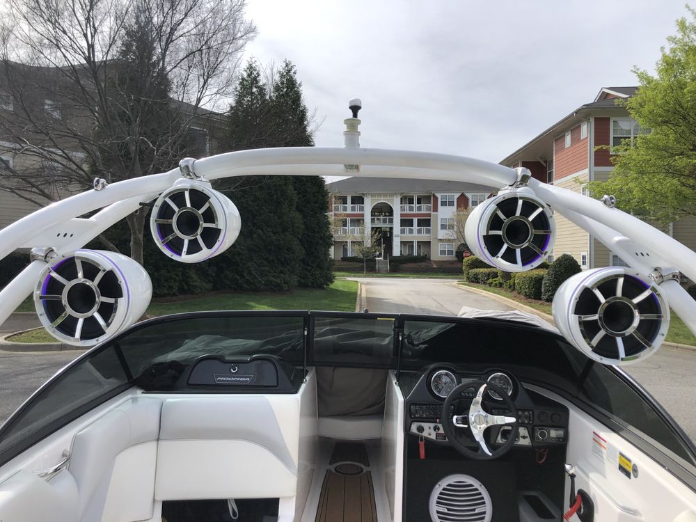 A boat with speakers on the top of it is parked in front of a house.