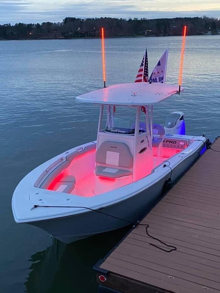 A white boat is docked at a dock with red lights on it.