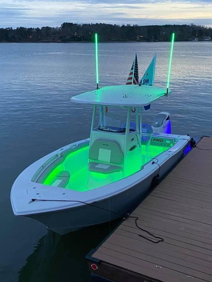 A boat is docked at a dock with green lights on it.