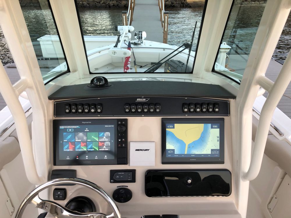 The cockpit of a boat with two monitors and a steering wheel