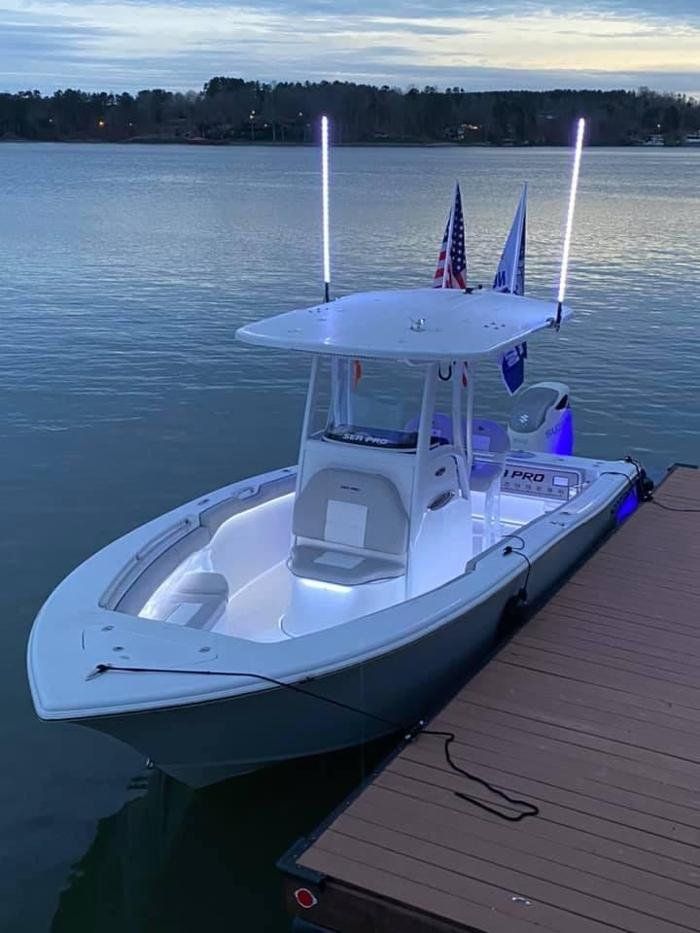 A white boat is docked at a dock in the water.