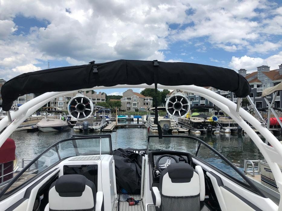 A boat with speakers on the top of it is docked in a marina.