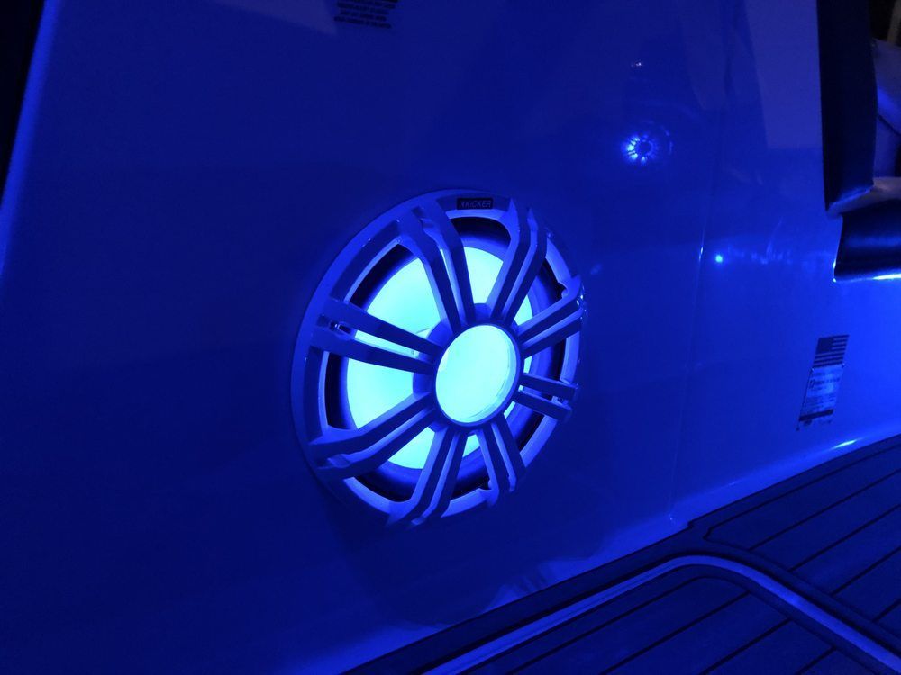 A blue light is shining on a speaker on the side of a boat.